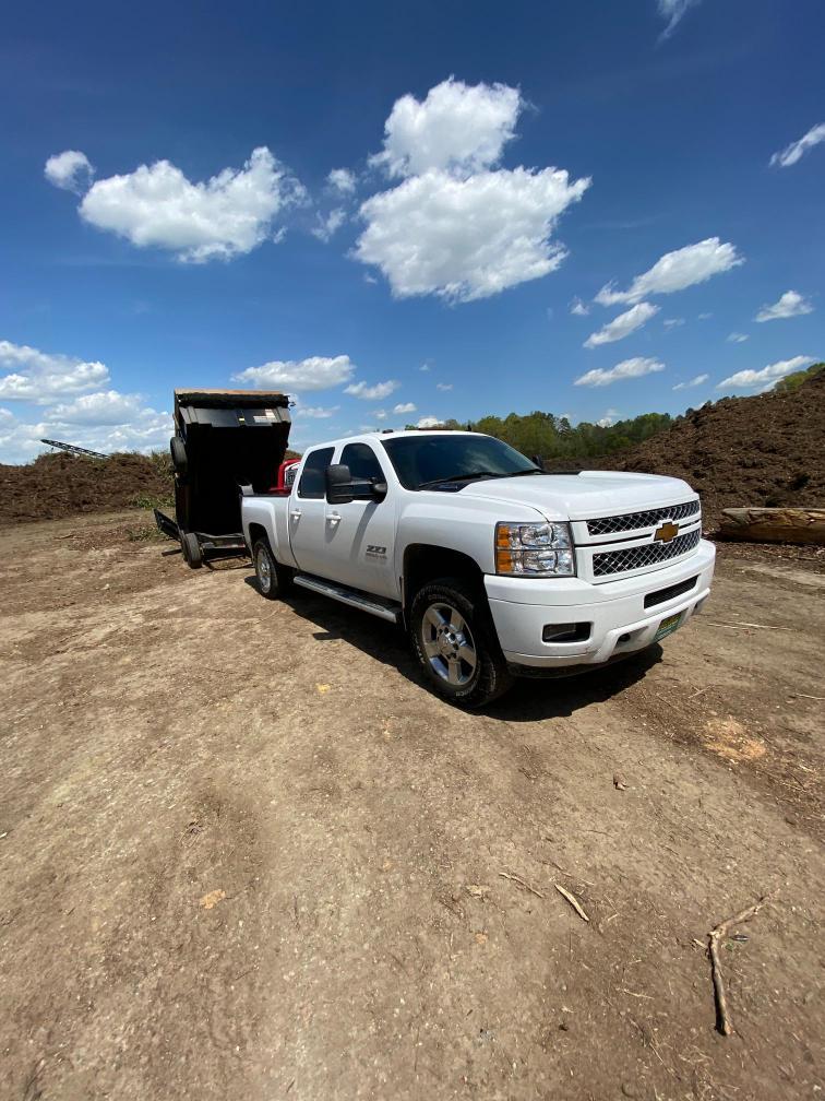 White pickup truck towing trailer at dirt worksite
