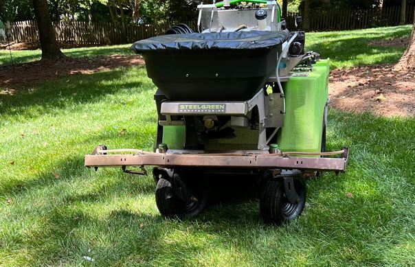 Steel Green lawn treatment spreader parked on grass