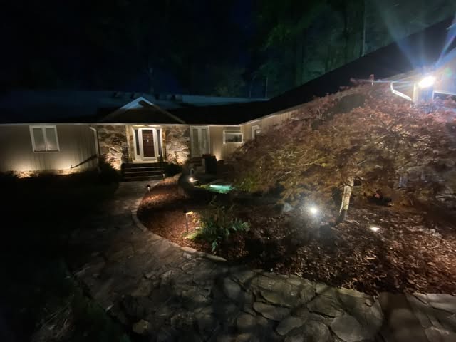 Illuminated house entrance and landscaped garden at night