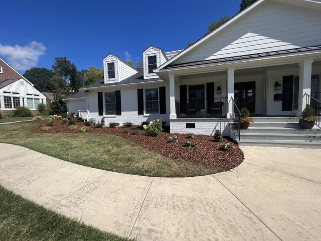 White farmhouse with black shutters and landscaped front yard