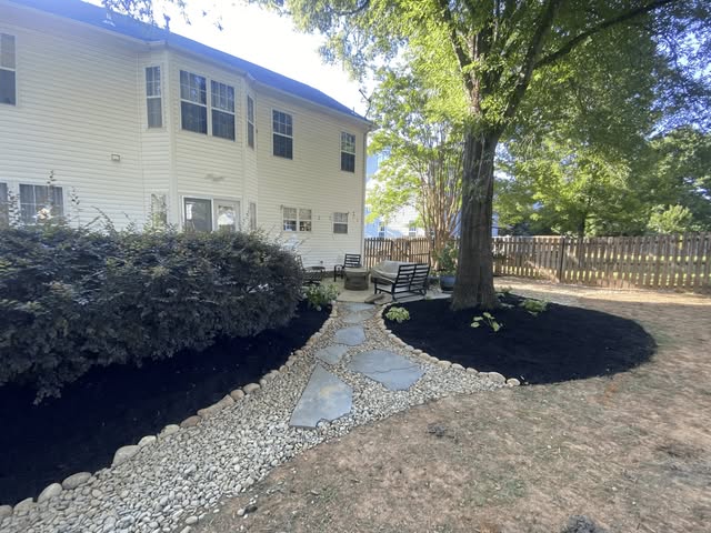 Landscaped backyard with stone path, benches, and shade tree