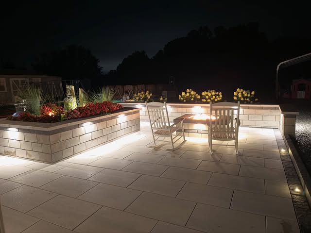 Illuminated backyard patio with rocking chairs at night