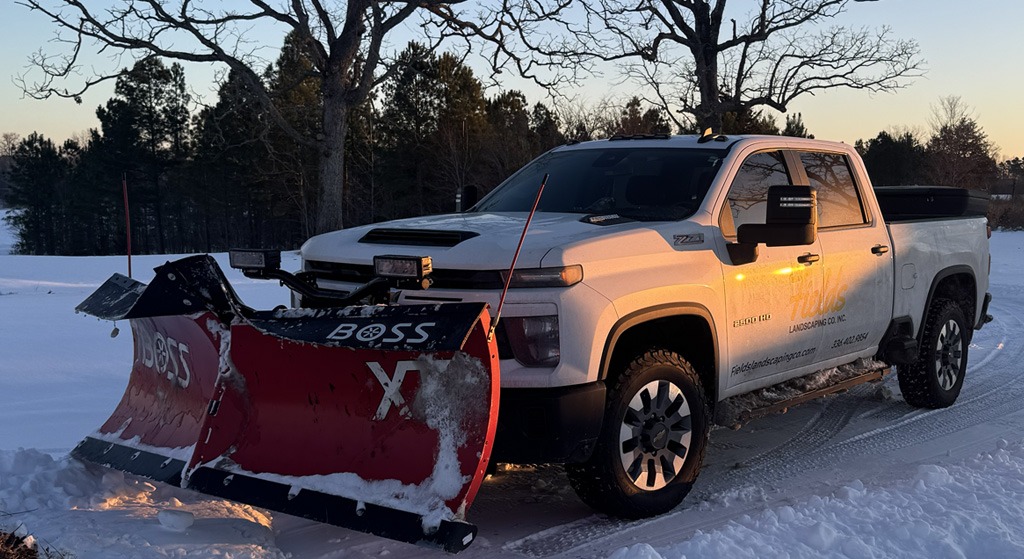 White pickup truck with snowplow in snowy driveway