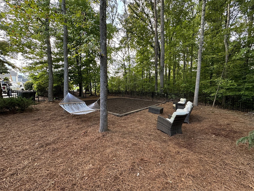 Wooded backyard patio with hammock and wicker chairs