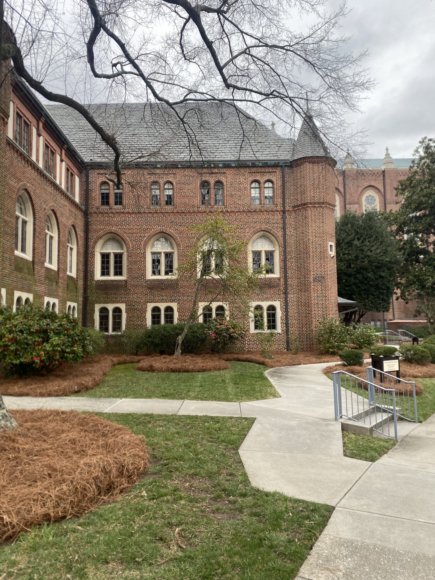 Historic brick building with arched windows and landscaped walkway