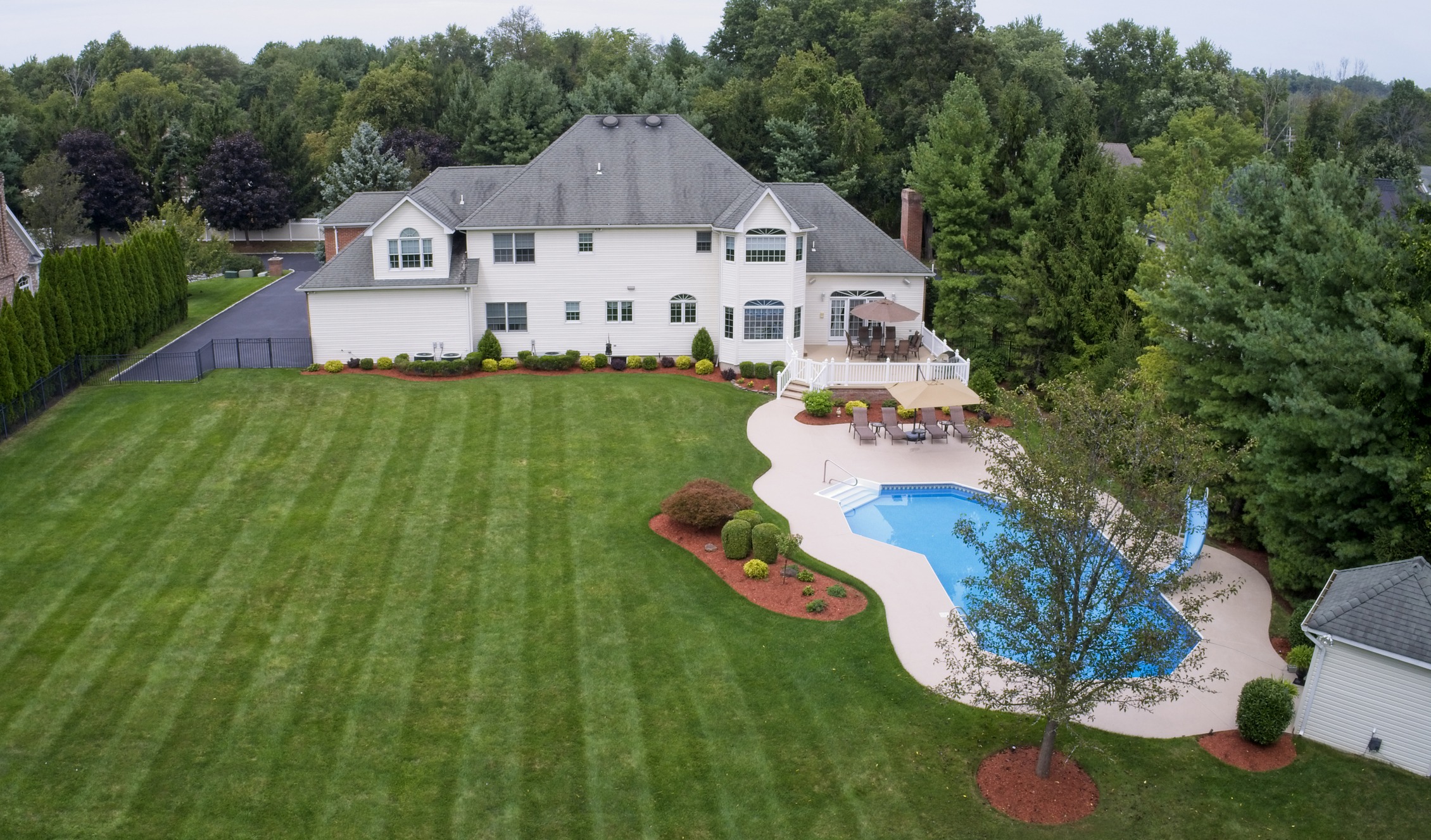 Aerial view of suburban home with pool and lawn