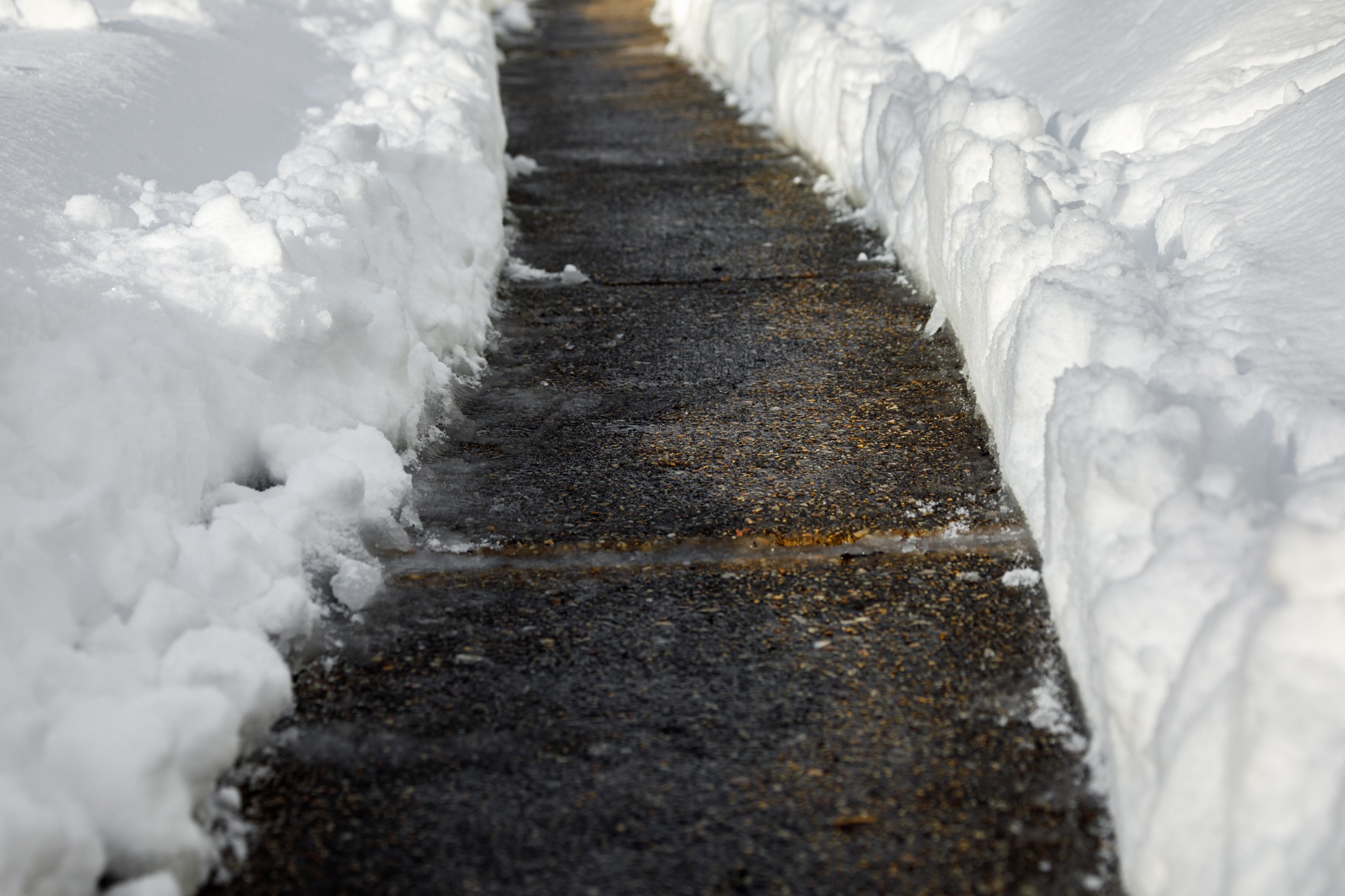 Cleared sidewalk bordered by high banks of snow