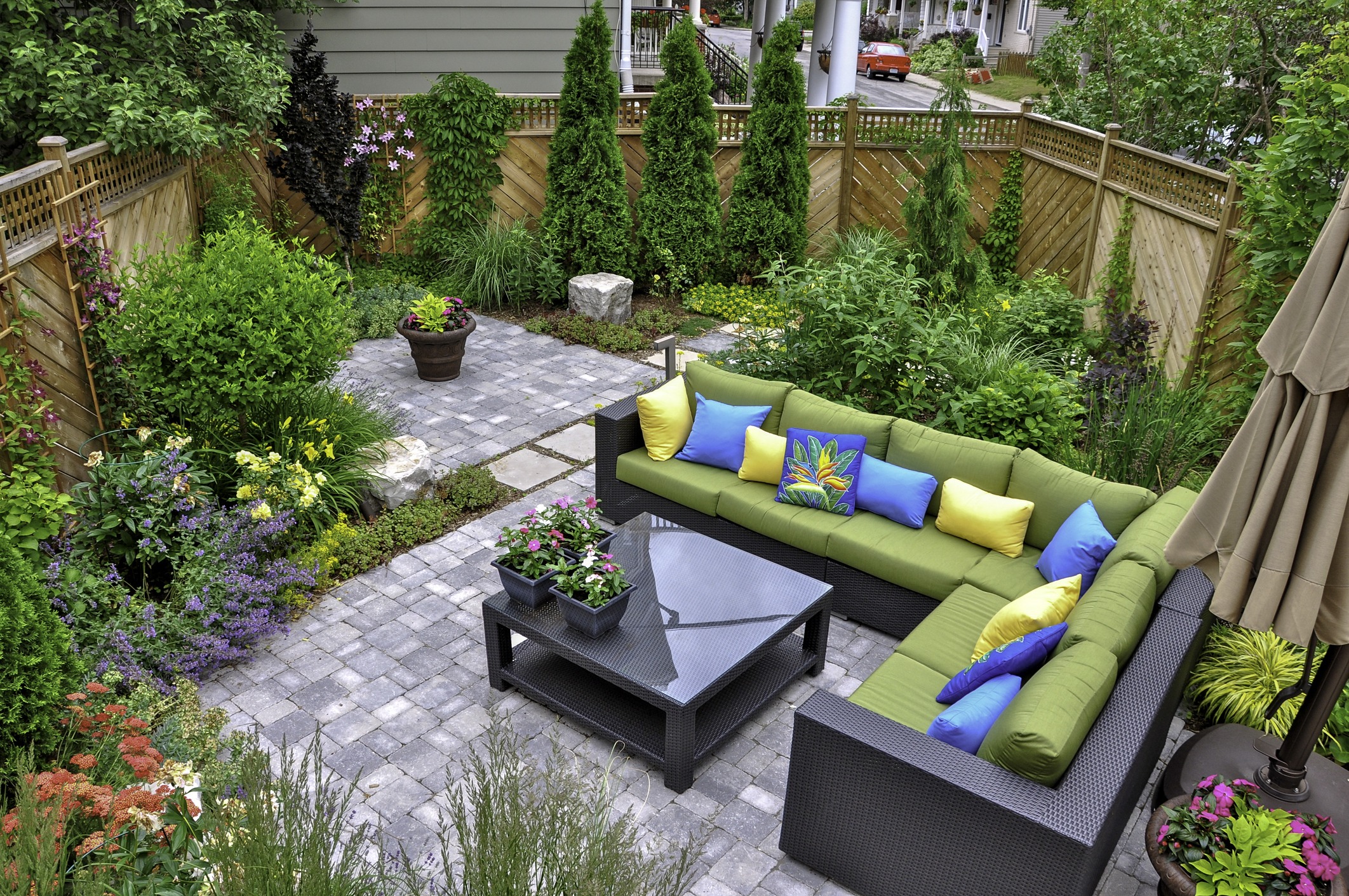 Lush garden patio with green seating and colorful pillows