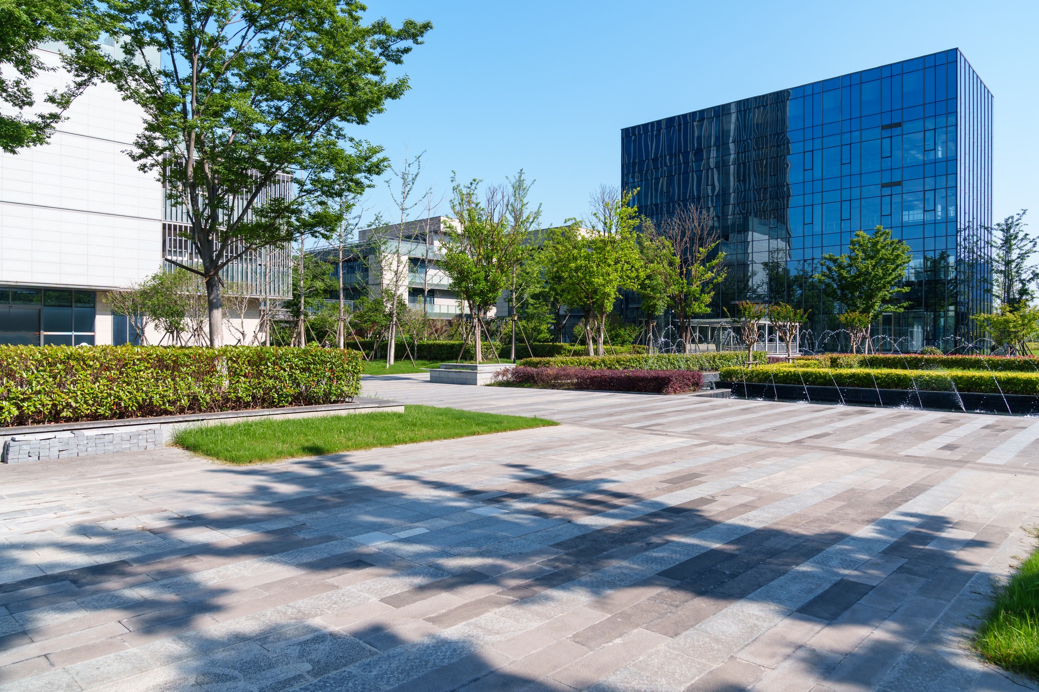 Modern glass office building beside landscaped courtyard fountain