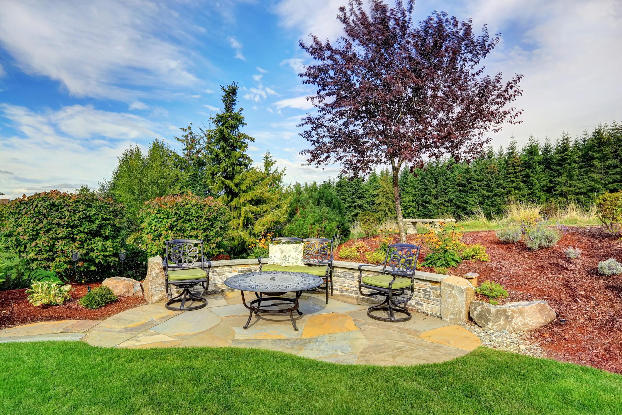 Stone patio seating in a lush landscaped garden