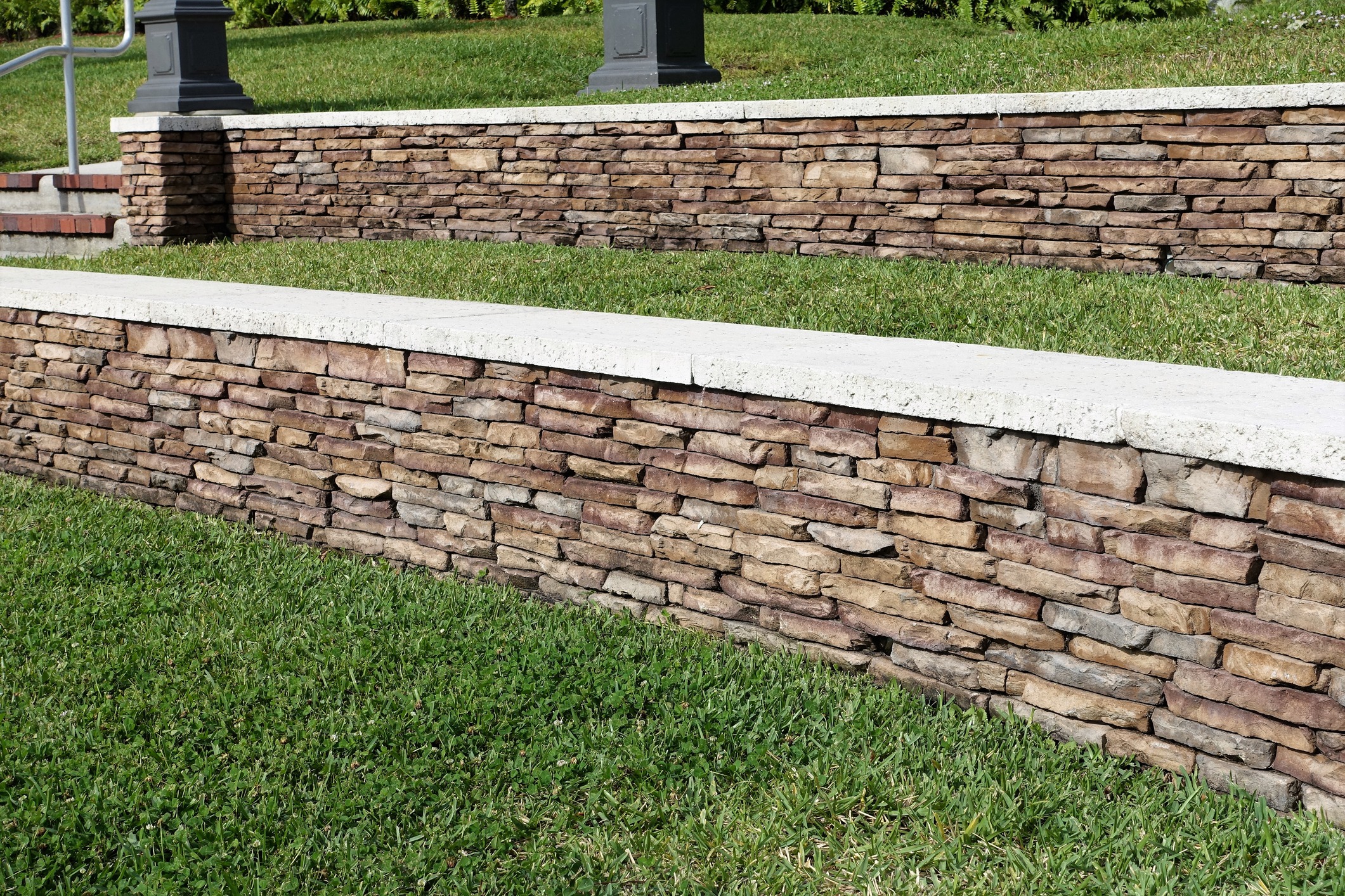 Tiered stacked-stone retaining walls beside a grassy lawn
