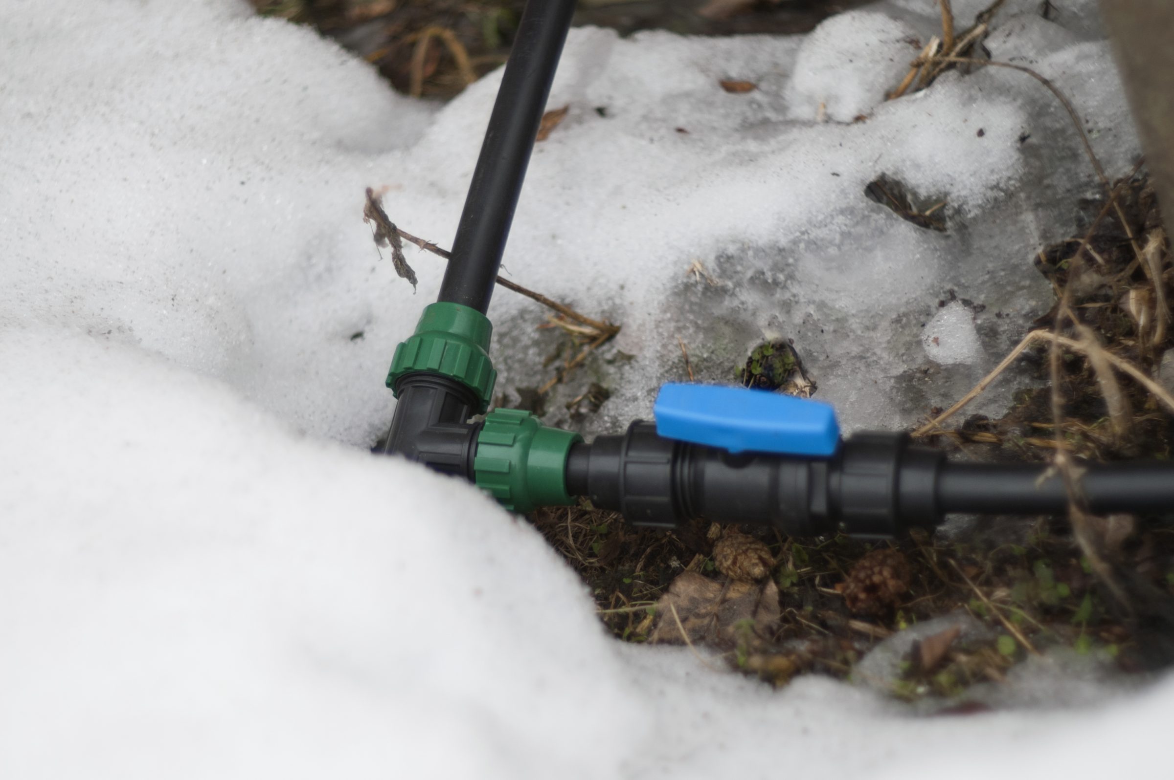 Irrigation valve and pipe connection surrounded by melting snow